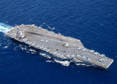 A photograph of an aircraft carrier sailing through the ocean