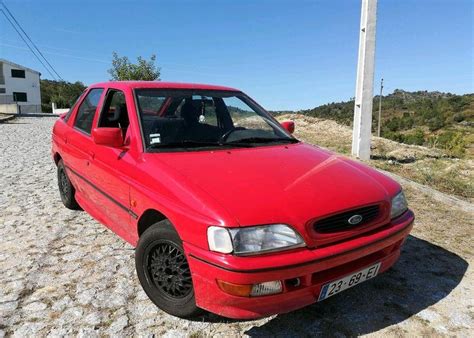 A classic 80s Ford Escort parked on the side of the road