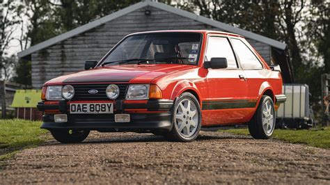 A classic 80s Ford Escort parked in a garage