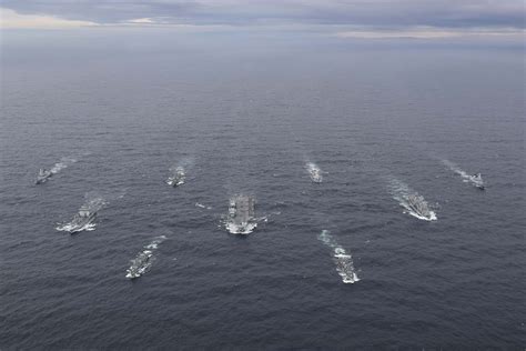 A photograph of a modern naval fleet sailing through the ocean