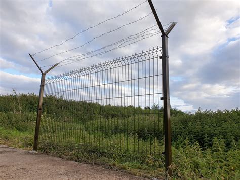 A modern barbed wire fence surrounding a farm