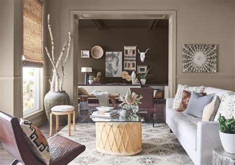 A living room with cream-colored walls and taupe-colored furniture featuring bold patterns