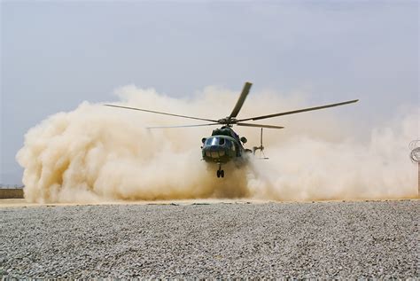 A helicopter landing in a field, with people watching from the sidelines