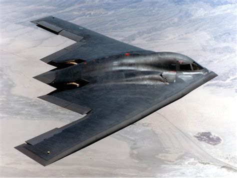 A stealth bomber flying over a mountain range